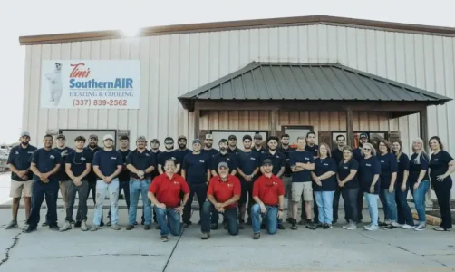 Large group of Southern Air Heating & Cooling employees in navy and red uniforms standing together in front of their facility building.